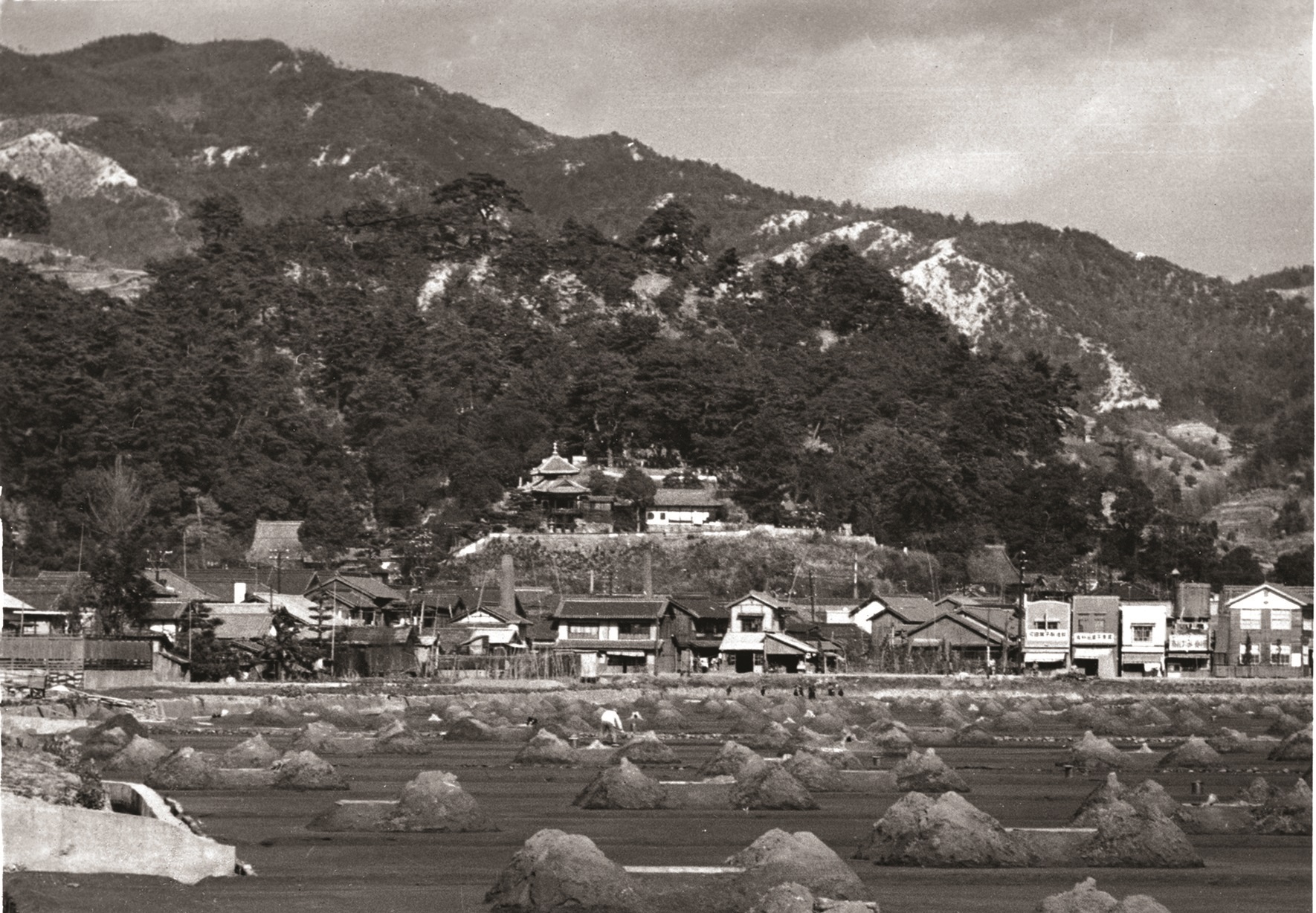 遠くに山々が見える閑散とした街並みの白黒写真