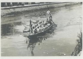 ボートに大勢の人が乗って一斉にオールを漕いでいる白黒写真