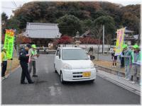 白い車に交通安全のノボリを見せている参加者の様子の写真