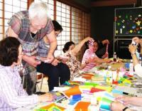 子どもや大人やご老人が折り紙を楽しんでいる様子の写真