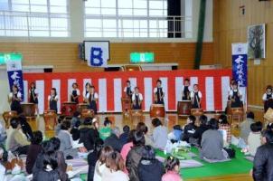 同じ衣装で太鼓を演奏している子ども達とそれを聴いているお客さんたちの写真
