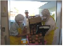 エプロンを付けた2人が納品された食料を受け取る様子の写真