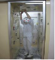 エアシャワーの中でホコリなどを吹き飛ばしている給食調理員の写真