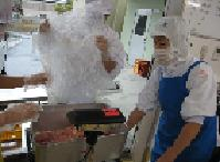 肉の品質チェックをしているエプロン姿の給食調理員の様子の写真