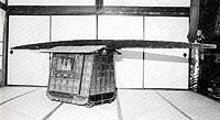 畳部屋の中央に置かれている漆塗りの駕篭の白黒写真