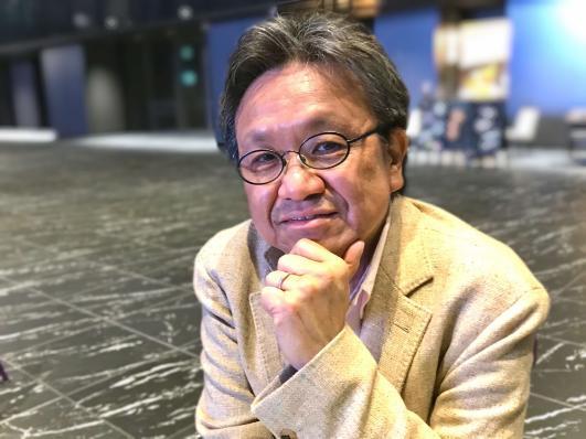 黄色いスーツを着て撮影された佐藤順一さんの写真