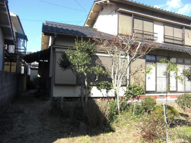 様々な木々の奥に佇む住宅の写真
