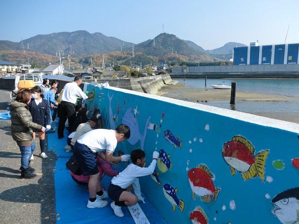 護岸に色を塗っている生徒たちの壁画が完成間近になっている写真