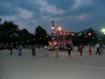 薄暗い広場で盆踊りをしている写真