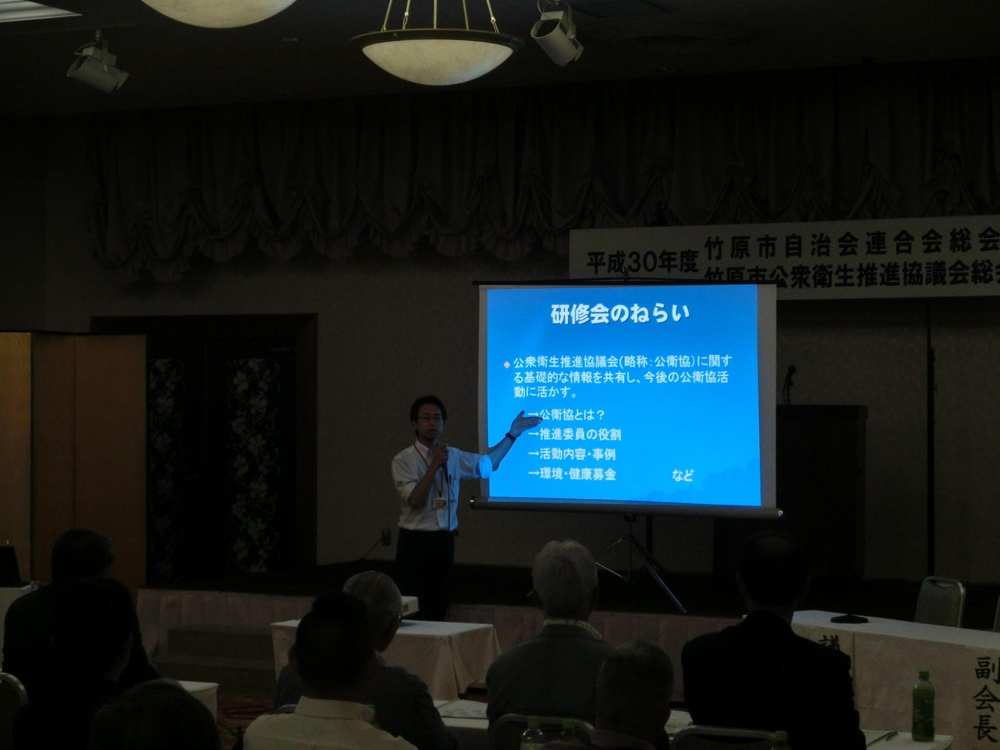 県の環境保健協会の先生が学習会でプロジェクターを使って説明をしている写真