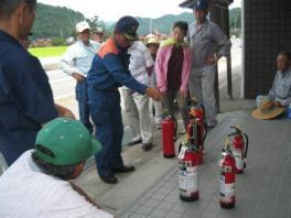 消化器を指差し説明している消防士の写真
