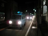 暗がりの中で道路に白いパトカーが走っている写真