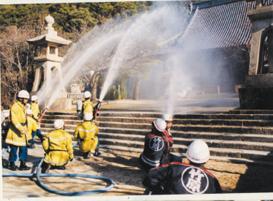 神社に放水をしている消防士たちの様子の写真