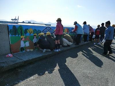 海沿いの防波堤に壁画を描いている小学生たちの写真