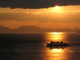 船がゆく海に反射している夕日の写真