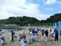 白いゴミ袋を片手に海岸の清掃をしているボランティアの皆さんの様子の写真