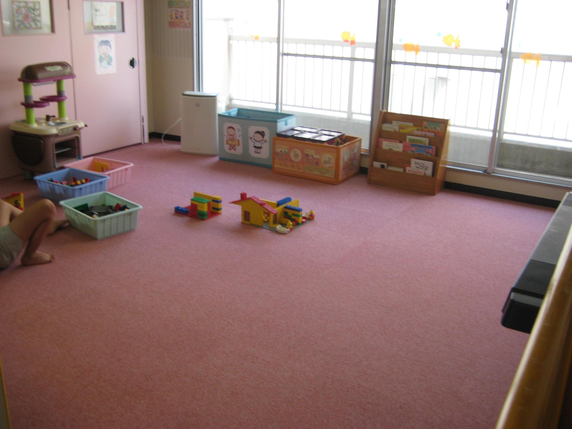 ピンク色の床に乳幼児用のおもちゃがある部屋の写真