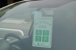 ルームミラーに取り付けられた、緑の「思いやり駐車場利用証」の写真