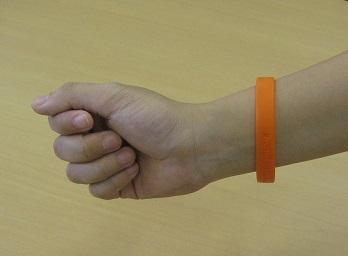 認知症サポーターの印のオレンジリングを腕に付けている写真