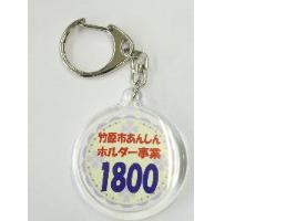 「竹原市あんしんホルダー事業」と数字が記載されている丸型の透明なキーホルダー表面の写真