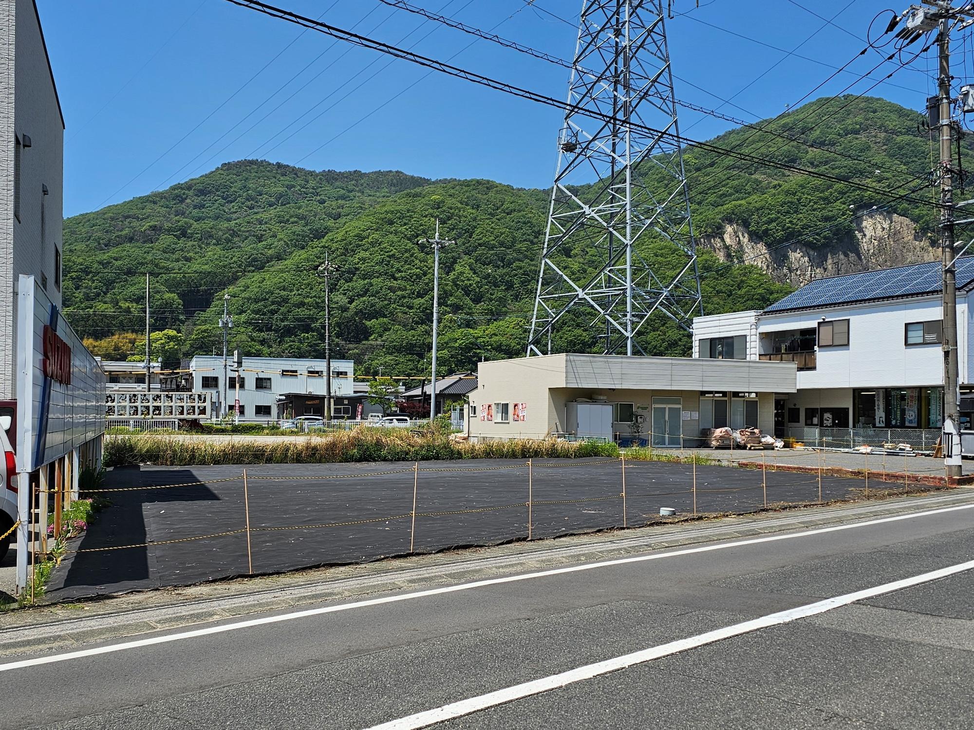 奥に平屋建てが見えるポールで囲まれた物件番号1の写真