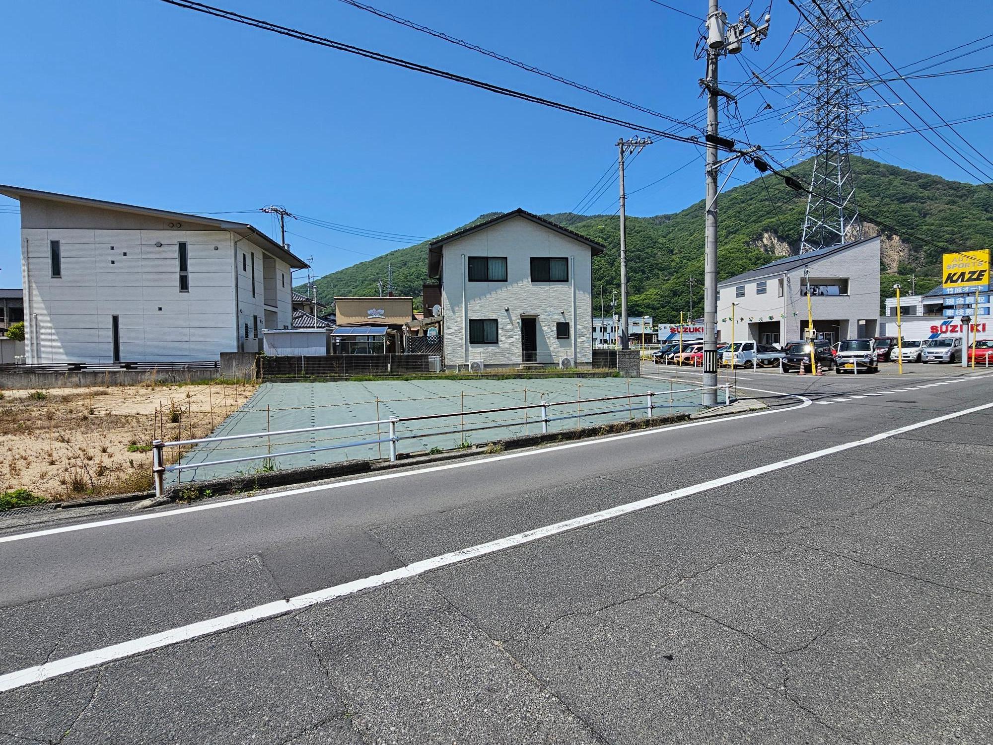 奥に平屋建てが見えるポールで囲まれた物件番号1の写真