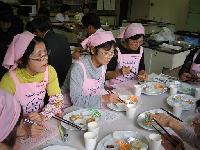 ピンクのエプロンを着た女性たちが食事をしている写真