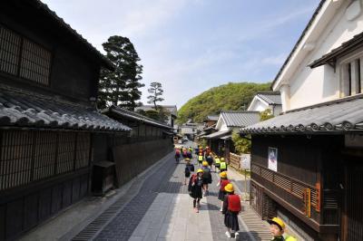 古民家が並ぶ道路を登校していく小学生たちの写真